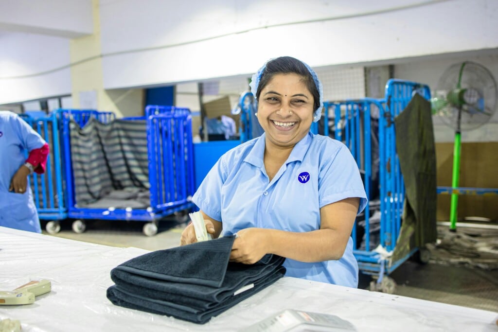 Laundromat Water Treatment 3 A textile worker folding clothes in a laundry facility.